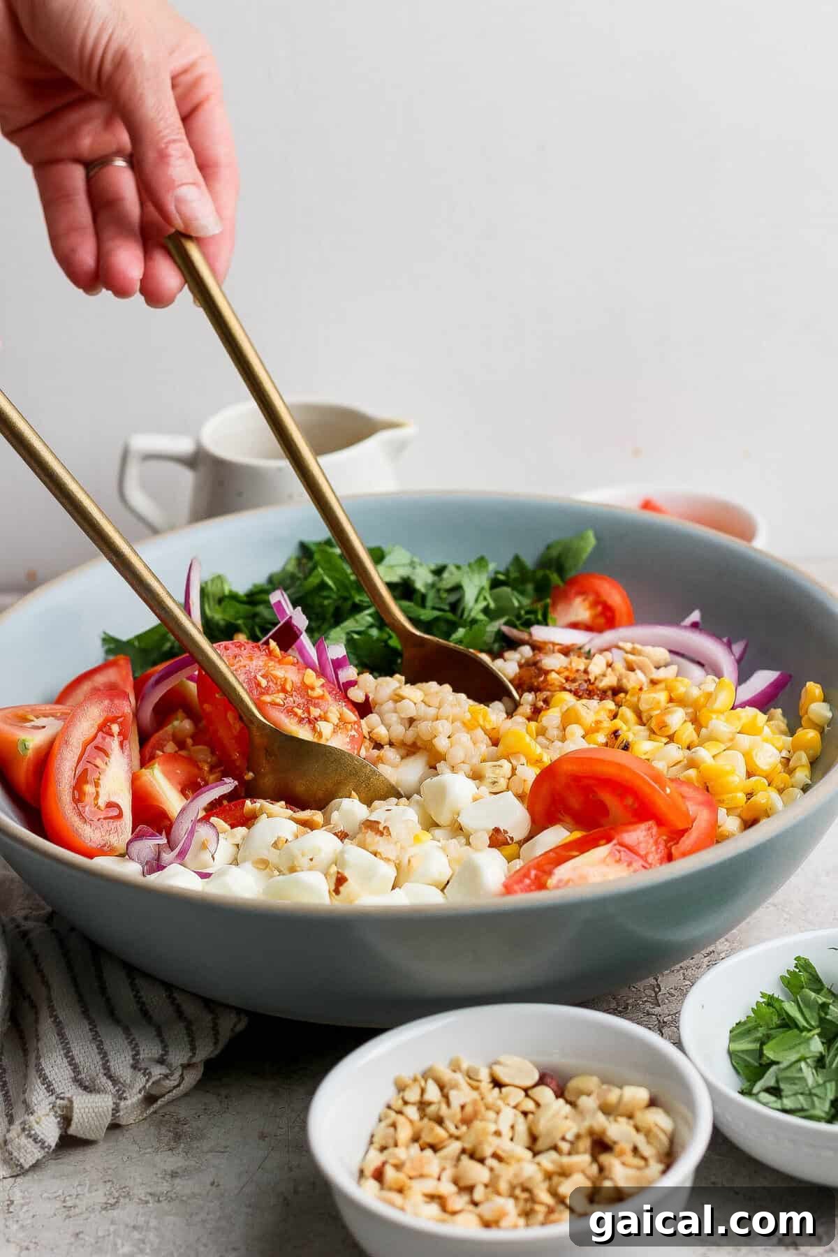 tossing corn tomato salad with chili crunch dressing in a large bowl