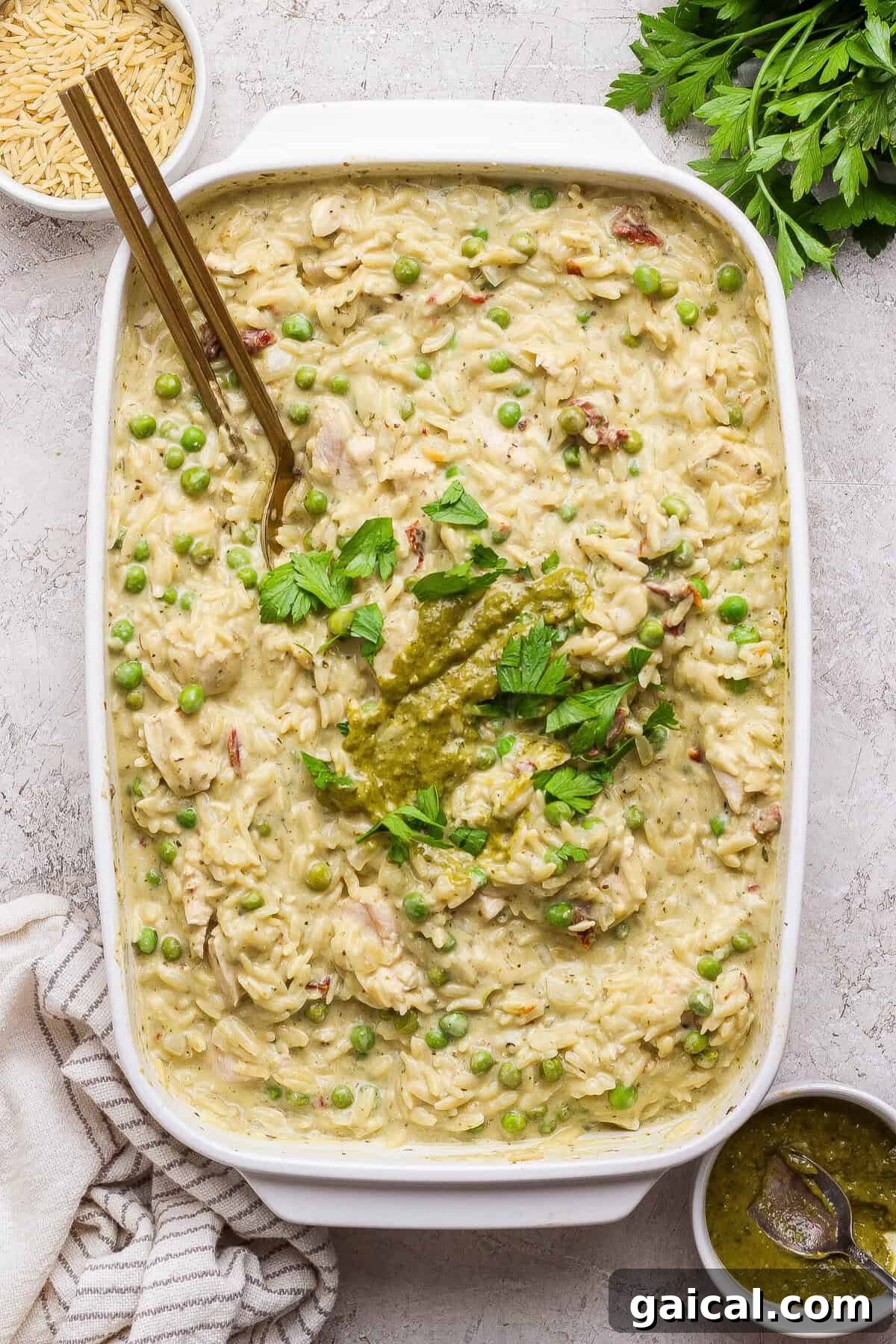 Finished creamy chicken pesto orzo casserole garnished with pesto and fresh parsley.