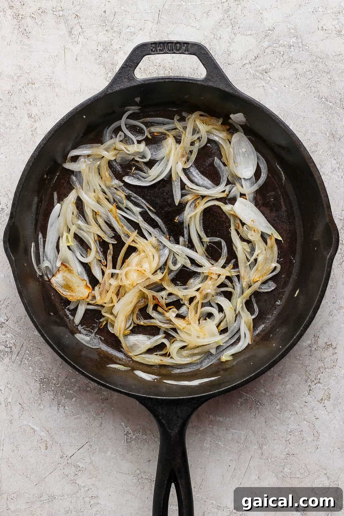 Soft golden sliced onions in a cast-iron skillet for cottage cheese French onion dip.