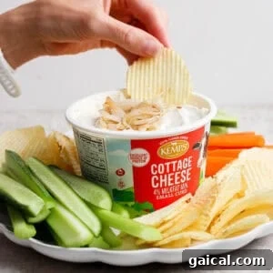 A ridged potato chip dipped into creamy cottage cheese French onion dip served with chips, carrots, and celery.