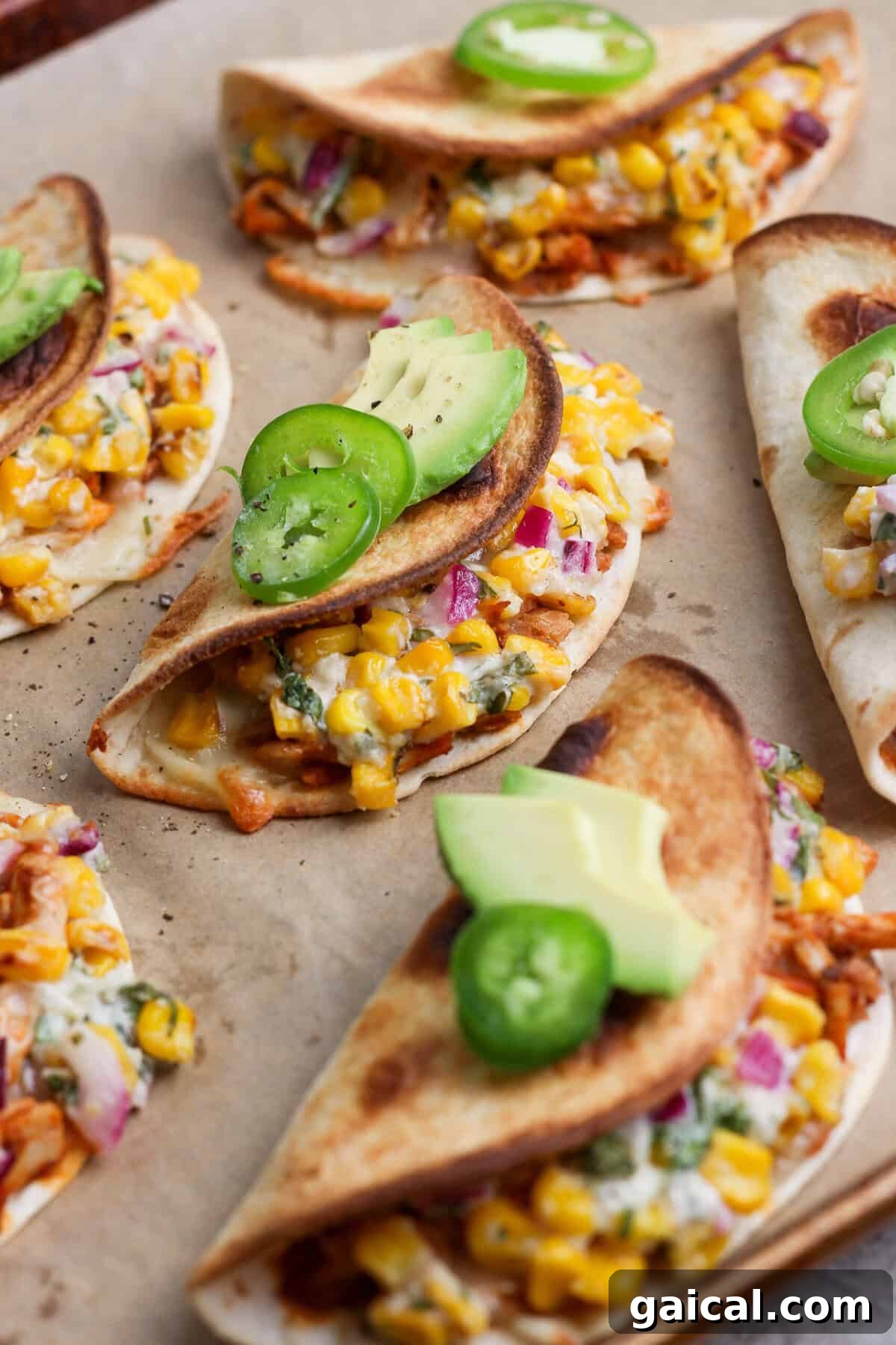 Crispy baked chicken tacos filled with creamy street corn salad and topped with avocado and jalapeño.
